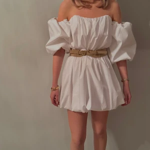 Vit offshoulder klänning  - Trendig vit offshoulder klänning med puffiga ärmar. Perfekt för en stilren look med en touch av elegans. Aldrig använt 
