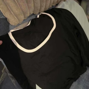 Svart och vit ärmlös topp - Säljer en stilren svart ärmlös topp med vita kanter. Perfekt för en enkel och snygg look.