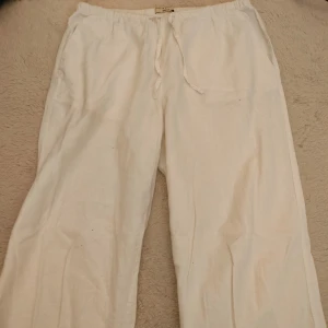 Vita linnebyxor från Gina Tricot - Snygga och bekväma vita linnebyxor från Gina Tricot. De har en loose passform med elastisk midja och snörning för extra komfort. Perfekta för varma sommardagar. Storlek S. De är uppsydda, innerbenslängd 69 cm.