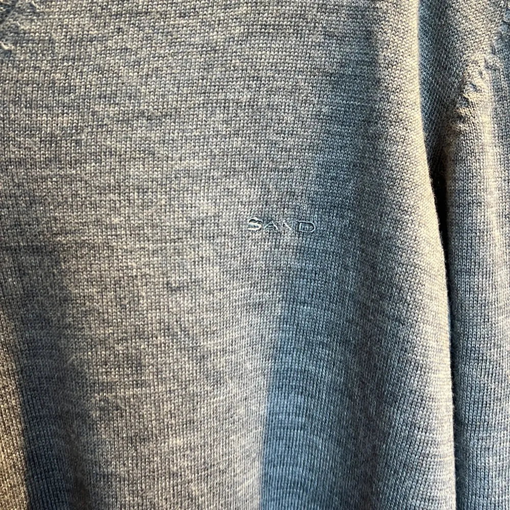 Snygg och stilren grå tröja från Sand med v-ringning. Perfekt för en klassisk look. Tröjan har långa ärmar och är tillverkad i ett mjukt material som ger en bekväm passform.. Neuletakit & Villapaidat.