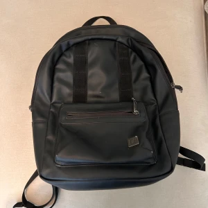 Svart ryggsäck från Douchebag  - Snygg svart ryggsäck från Db 16 l. Flera mindre fack, ett stort fack och ett datorfack. Använd och kantstött på några ställen men fint skick annars 