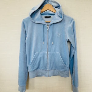 Juicy Couture Ljusblå zip hoodie stl S  - Säljer en snygg ljusblå hoodie från Juicy Couture. Den är tillverkad i mjuk polyester med en dragkedja framtill och har en klassisk huva. Perfekt för en avslappnad stil. Färgen är baby blue💙