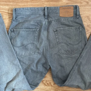 Grå jeans från Jack & Jones - Säljer ett par grå jeans från Jack & Jones i modellen Relaxed/Chris. De har en avslappnad passform och är tillverkade i ett slitstarkt material. Perfekta för en casual look.
