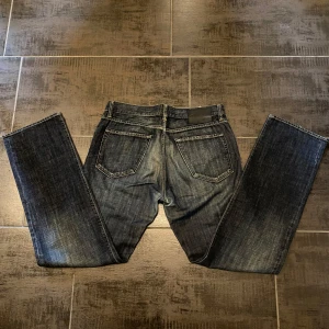 Mörkblå jeans från Hugo Boss - Snygga mörkblå jeans från Hugo Boss med klassisk femficksdesign och subtila slitningar. De har en rak passform och är perfekta för en stilren look. Märkeslogga på baksidan av midjan. Priset är ej hygget i sten!