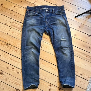 Blå jeans från Ralph Lauren - Säljer ett par blå jeans från Ralph Lauren, Denim & Supply. De har en tapered straight passform och en snygg sliten look med en reva på ena benet. Perfekta för en avslappnad stil.