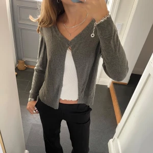 Grå stickad kofta  - Stickad grå kofta från Road i fint skick. Kan inte hitta storlek men skulle säga S/M. Verkar vara meningen att man ska kunna dra ett snöre genom kragen då den är ihålig (sista bilden). Använd gärna köp nu!