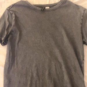 Grå t-shirt från H&M Divided - Säljer en enkel och stilren grå t-shirt från H&M Divided. Perfekt för en avslappnad look. T-shirten har korta ärmar och en rund halsringning.