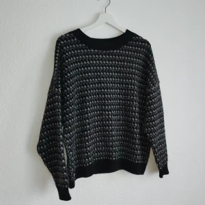 Mönstrad stickad tröja från Mango - Säljer en snygg stickad tröja från Mango med ett unikt mönster i svart och grått. Tröjan har långa ärmar och en bekväm passform, perfekt för kyligare dagar. Ett stilrent val för garderoben!