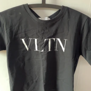 Svart t-shirt från Valentino - Snygg svart t-shirt från Valentino med VLTN-tryck i vitt på framsidan. Perfekt för en stilren look. T-shirten har en klassisk rund hals och korta ärmar.
