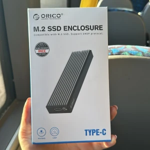 M.2 SSD Enclosure från Orico - Säljer ett M.2 SSD Enclosure från Orico, kompatibelt med M.2 SSD och stöd för UASP-protokoll. Den har en stilren design med en ribbad yta och anslutning via Type-C. Perfekt för snabb och säker dataöverföring.