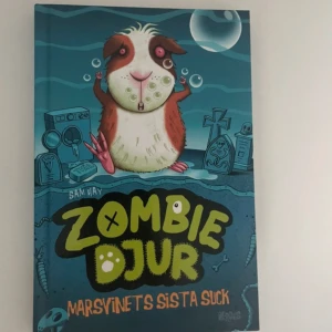 Zombie Djur: Marsvinets Sista Suck - En spännande bok om ett marsvin som blir en zombie. Följ med på ett äventyr där huvudpersonen kan prata med döda djur tack vare ett magiskt amulett. Perfekt för dig som gillar humor och äventyr med en twist av det övernaturliga.