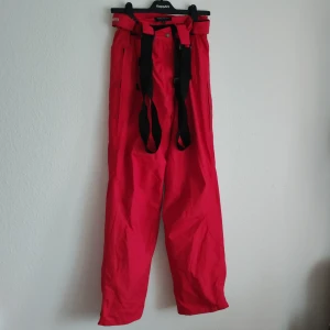 Röda täckbyxor från True North - Säljer ett par röda täckbyxor från True North, perfekta för kalla dagar. Byxorna har justerbara hängslen och knäppning i midjan för extra komfort. Designade för nordiskt väder, idealiska för vinteraktiviteter.