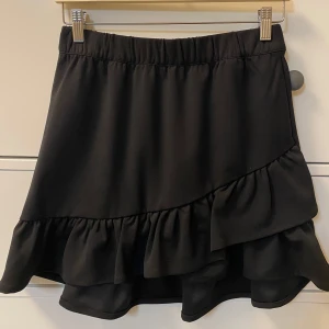 Svart kjol med volang Vero Moda Stl S - Snygg svart kjol med volang. Elastisk midja. Vero Moda stl S, sparsamt använd.