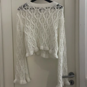 Vit stickad tröja från H&M Divided - Säljer en vit stickad tröja i storlek S från H&M Divided. Tröjan har ett vackert spetsmönster med utsvängda armar. Aldrig använt.