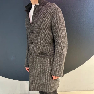 Grå stickad rock - Snygg grå stickad rock med knappar framtill. Den har en klassisk krage och långa ärmar, perfekt för kyligare dagar. Kappan har en stilren design som passar till många olika outfits.