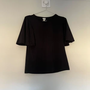 Svart blus med korta ärmar💗 - Snygg svart blus från H&M med korta ärmar och rund halsringning. Perfekt för en stilren look. Tröjan är i ett väldigt skönt material, typ som träningskläder💗