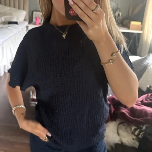 Mörkblå topp - sommar25 - Säljer en mörkblå topp med korta ärmar. Perfekt för en avslappnad look. Toppen har en enkel design som gör den lätt att matcha med olika outfits.