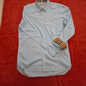 Burberry skjorta - En fin burberry skjorta i storlek M färg ljusblå. Den är i strålande skick. Priset är inte hugget i sten. 