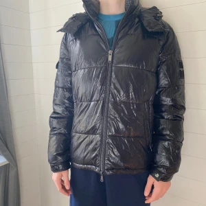 Svart pufferjacka från Michael Kors - Säljer en snygg svart pufferjacka från Michael Kors i storlek S. Den har en dragkedja framtill och en praktisk huva. Jackan är i nyskick, något skrynklig efter sommarförvaring men hänger till sig. Skicka för fler foton. 
