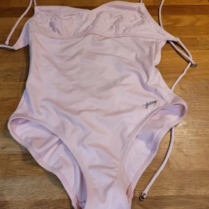 Ursnygg rosa baddräkt från Juicy Couture st M - En rosa baddräkt jättefina detaljer och knytband från Juicy Couture. Baddräkten har en djup urringning i ryggen. Aldrig använd. Så mycket snyggare i verkligheten, måste upplevas! Storlek M, men tror den passar en S - 36/38 bäst.