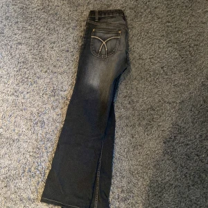 Svarta bootcut jeans - Säljer ett par snygga svarta bootcut jeans med coola detaljer på bakfickorna. De är i bra skick och har en skön passform. Perfekta för både vardag och fest!