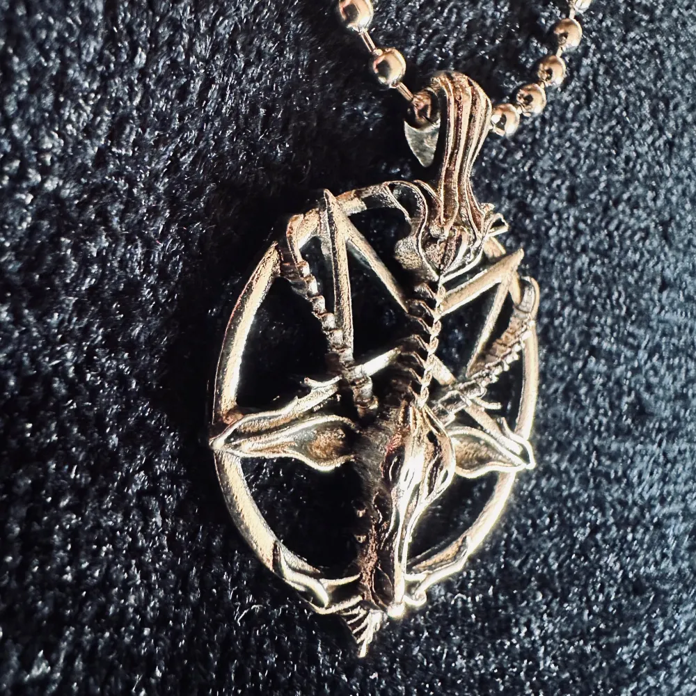 Silverfärgat halsband med pentagram i form av Baphomet, ibland kallad getguden eller bockguden från Mendez.   Amuletten är cirka 3,5 cm lång och 2,5 cm bred.   Kulkedjehalsbandet är ca 48 cm långt.  Nytt och i perfekt skick.   Jag prutar inte. . Accessoarer.