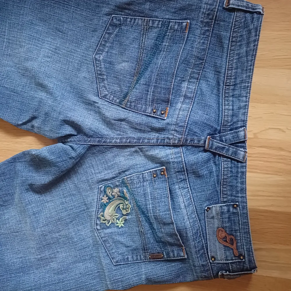 Blå jeans, mid-waisted, med grön detalj på ena bakfickan, bra kvalitet. Uppsprätt ankelsöm. (Jag är 167cm). Jeans & Byxor.