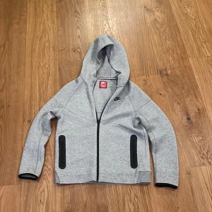  Grå Nike Tech fleece - Hej! Jag säljer denna Nike Tech  som är för liten för mig. Den är sprillans ny och fläckfri. Storleken är Xl junior. Ny Nike tech kostar ca 1100, jag säljer denna för 500. Pris kan diskuteras.  