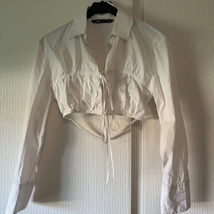 Zara Croppad skjorta med detaljer  - Snygg croppad skjorta från Zara med fina detaljer i ryggen och fram. Använd ett fåtal gånger, skriv vid fler frågor