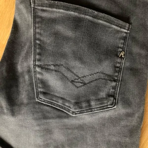 Svarta jeansbyxor från Replay, anbass hyperflex - Säljer ett par svarta Replay Hyperflex jeans i mycket bra skick. De är slim fit och har en snygg, modern look. Perfekta för både vardag och fest! Skick 9/10. Färg beskrivs bäst i bild ett. Hör av er vid minsta fråga/fundering.