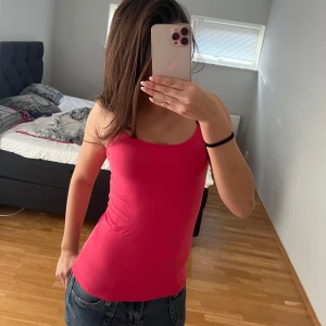 Rosa linnetopp - Säljer en snygg rosa linnetopp i ett mjukt och stretchigt material. Perfekt för sommardagar eller som ett lager under en jacka. Toppen har en enkel design med smala axelband och en figurnära passform. Passar både till vardags och fest!