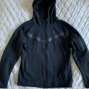 Nike fleece tech svart M 137-147 cm - En svart Nike fleece tech i gott skick. Den har blivit för liten. Fortfarande grymt snygg och fräsch. Nikes medium för juniorer 137-147 cm lång. 