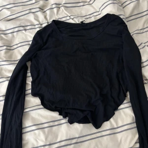 Svart ribbad långärmad topp - Säljer en svart ribbad långärmad topp i bra skick. Den är croppad och har en snygg passform som passar perfekt till både vardag och fest. Toppen är gjord i ett mjukt och stretchigt material som gör den bekväm att bära hela dagen.