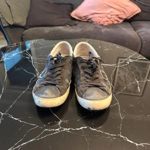 Mörkblåa  sneakers från Philippe Model - Säljer ett par mörkblåa sneakers från Philippe Model i använt skick. De har en klassisk design med snörning och en vit sula som ger en snygg kontrast. Perfekta för vardagsbruk och passar till det mesta i garderoben.