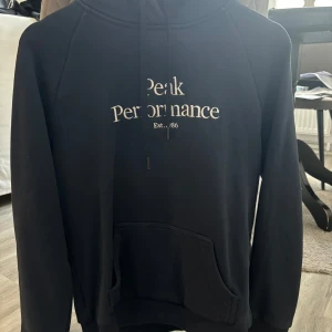 Svart hoodie från Peak Performance - Säljer en svart hoodie från Peak Performance i bra skick. Den har en klassisk design med vit text på framsidan och en stor ficka. Perfekt för höst och vinter, och den är superbekväm att ha på sig. Passar både till vardags och chillkvällar. 🖤