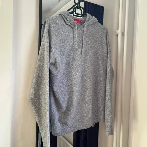 Stickad Hoodie - Mysig grå hoodie i bra skick ändats avdvänd 2-3 gånger. Perfekt för kyliga dagar med sin mjuka och bekväma passform. Den har en klassisk design med huva och långa ärmar. Passar både för vardag och avslappnade tillfällen. Storleken är märkt 146-152 men jag skulle säga att den passar ungefär 160