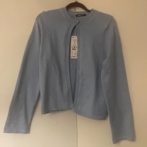 Ljusblå kofta från Gina Tricot - Säljer en superfin ljusblå kofta från Gina Tricot i nytt skick. Den är stickad och har långa ärmar med en enkel knapp framtill. Passar till både vardag och fest! 💙nytt skick, köpt för 350kr