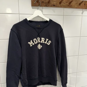 Svart sweatshirt från Morris - Säljer en snygg svart sweatshirt från Morris i storlek M. Tröjan har ett klassiskt tryck med Morris-loggan på framsidan. Perfekt för en avslappnad stil och passar bra till både jeans och chinos. Den är i bra skick! Sitter som en mindre M