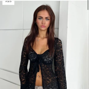 Svart spetsblus - Snygg svart spetsblus med knyt framtill. Den är långärmad och har en elegant, genomskinlig look som passar perfekt för festliga tillfällen. Den är i bra använt skick. Säljer för 240 + frakten🌸strl M/L, sitter dock som en S/36