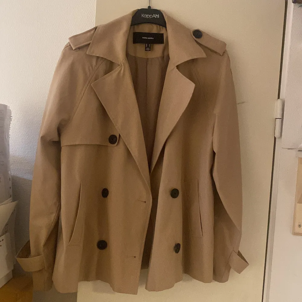 Säljer en snygg beige trenchcoat från veromoda i mycket bra skick. Jackan har en klassisk design med dubbelknäppning och stora knappar. Perfekt för höst och vår, med långa ärmar och stiliga detaljer vid axlarna. Passar både till vardags och lite finare tillfällen. Strl M. Jackor.