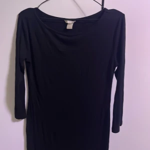 Svart ribbad klänning från Basic - Säljer en stilren svart klänning från Basic i storlek M. Den har en ribbad struktur och långa ärmar, perfekt för både vardag och fest. Klänningen är i bra skick och passar till många olika tillfällen.