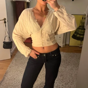 Beige blus med spetsdetaljer - Säljer en superfin beige blus med spetsdetaljer och knappar framtill. Den är croppad och har långa ärmar med en lös passform. Perfekt för både vardag och fest! 💫