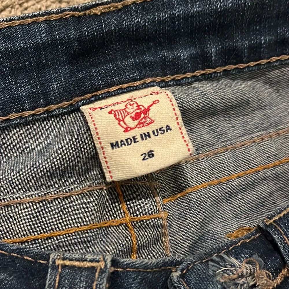 Säljer ett par snygga blå jeans från True Religion i storlek 26. De är i bra skick och har en cool broderad detalj på bakfickan, ena knappen saknas men man kan ta bort båda eller flytta den andra knappen 😁. Jeans & Byxor.