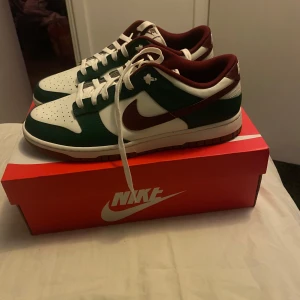 Nike Dunk i grönt och vinrött - Säljer ett par Nike Dunk i grönt och vinrött. Skorna är helt nya och köpta på Nike allt og tillkommer