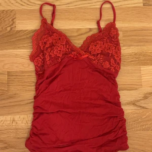 Röd linne med detaljer - Rött linne med detaljer. bra skick använd få gånger. går att justera banden och väldigt stretchigt material.
