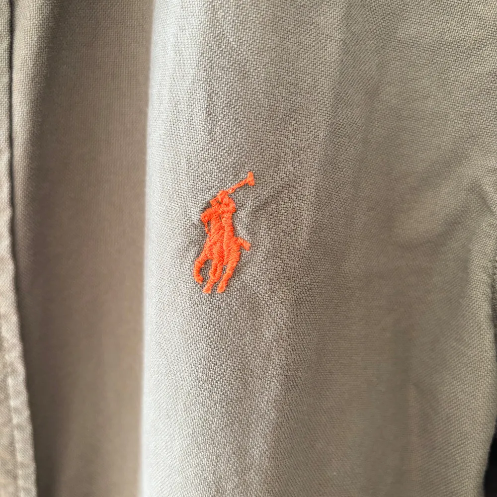 Säljer en snygg olivgrön skjorta från Ralph Lauren i slim fit. Skjortan har långa ärmar och klassiska knappar framtill. Den är broderad med Ralph Laurens ikoniska logga i orange på bröstet. Perfekt för både vardag och fest! 💛Väldigt bra skick 10/10. Skjortor.