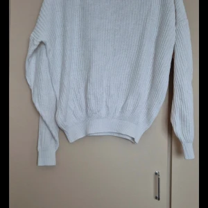 Vit stickad tröja från Quick Response - Säljer en stilren vit stickad tröja från Quick Response, tillverkad i Danmark. Tröjan har en klassisk design med ribbade detaljer vid ärmslut och nederkant. Perfekt för kyliga dagar och kan enkelt matchas med olika outfits. Passar både till vardags och lite finare tillfällen.