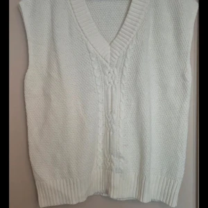 Vit stickad väst från Ellos - Säljer en superfin vit stickad väst från Ellos i storlek 38/40. Den har en snygg v-ringning och ett klassiskt flätmönster framtill. Perfekt för lager-på-lager under höst och vinter. Passar både till vardags och fest!