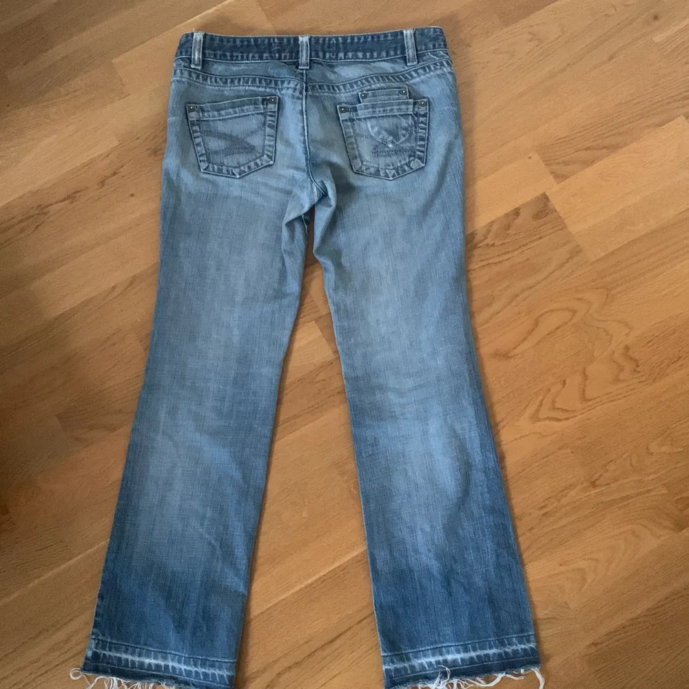 Säljer ett par snygga blå jeans i bra skick. De har en bootcut-stil och coola fransar vid bensluten. Perfekta för en avslappnad look! 🕶️. Jeans & Byxor.