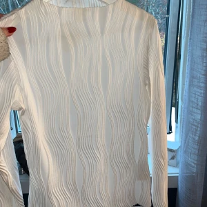 Vit ribbad långärmad tröja - Säljer en stilren vit tröja med ribbad struktur. Den är långärmad och har en tight passform som sitter snyggt på kroppen. Perfekt för både vardag och festliga tillfällen. Passar bra till jeans eller kjol för en chic look! Köptes för 650kr säljs för 200!🥰